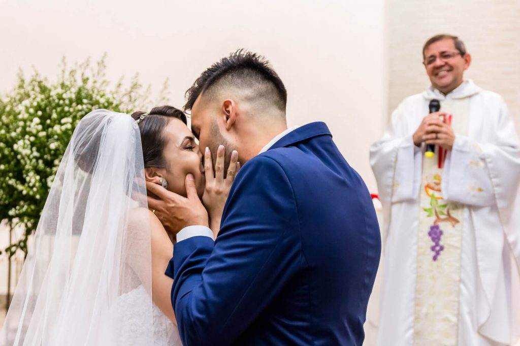 beijo noivos padre sorrindo altar casamento igreja BH